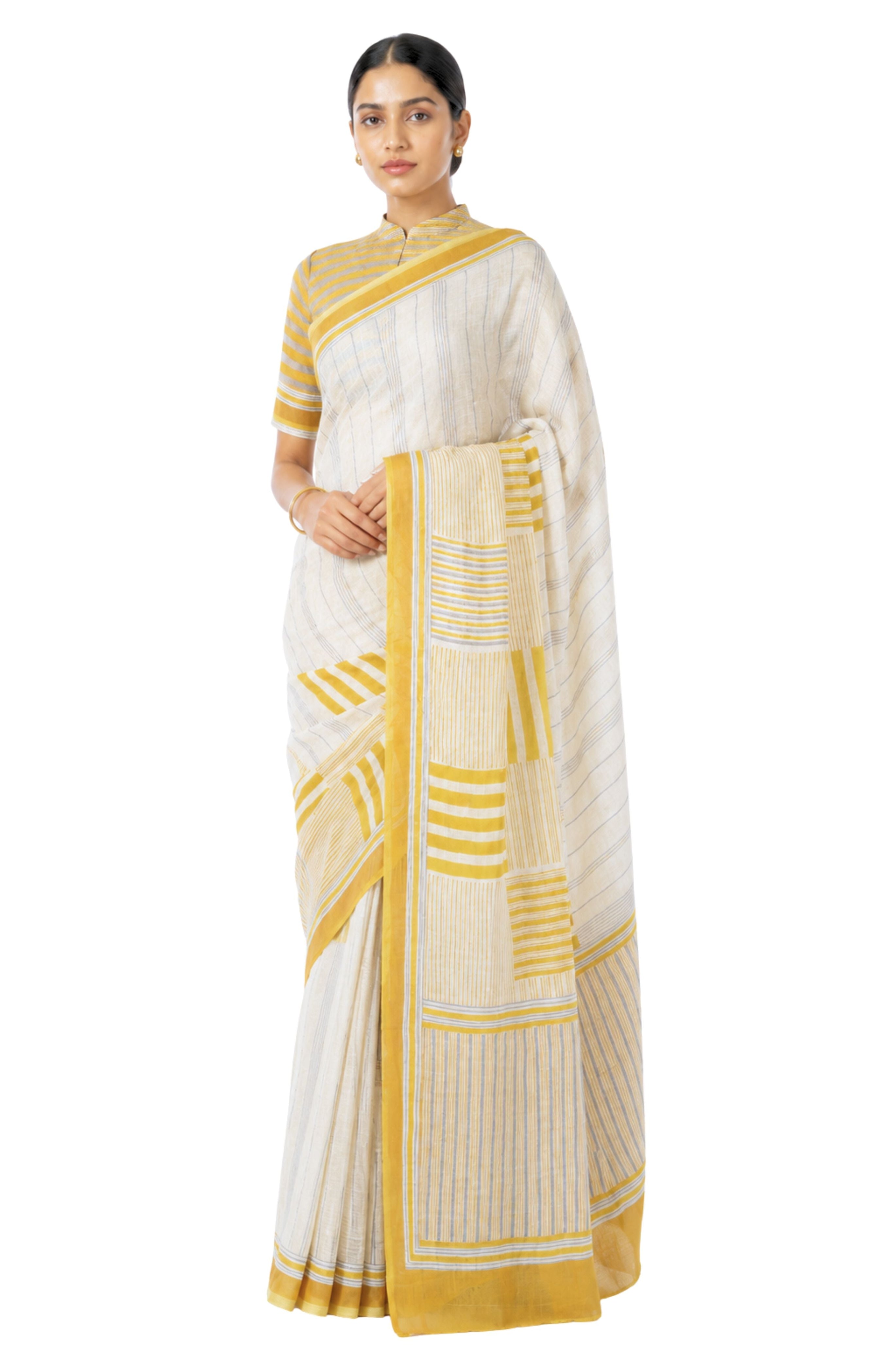 A woman modeling a white and yellow striped cotton saree with a yellow border, set against a plain white background.